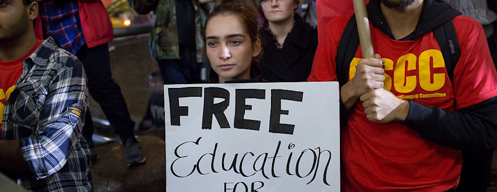 College students protesting, holding sign that reads "Free education for all"