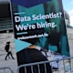 Attendees walk past a sign advertising for data scientists outside the Lisbon Web Summit venue in Lisbon, Portugal, on Monday, Nov. 7, 2016.