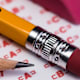 A closeup shot of the eraser end and the sharpened end of two #2 pencils laying on top of an paper SAT answer sheet.
