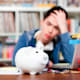 Piggy bank with young man worrying in background
